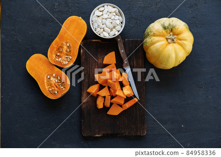 Cut pieces of raw pumpkin on wooden board on table Cut pieces of raw pumpkin on wooden board on table 84958336