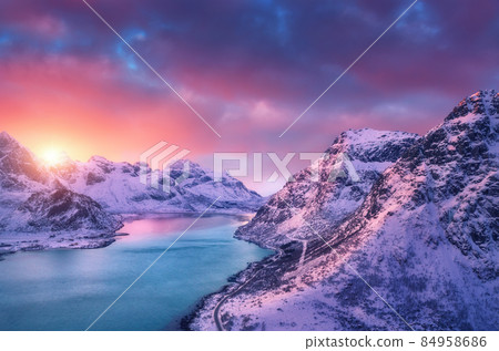 Aerial view of snowy mountains, sea, road, sky with pink clouds Aerial view of snowy mountains, sea, road, sky with pink clouds 84958686