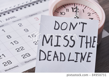Dont miss the deadline. Deadline text on piece of paper, alarm clock and monthly calendar on the desk. White card with Deadline text and last date of month. Last day, Last chance concepts 84958731