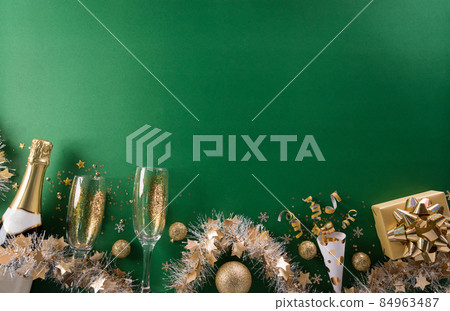 Happy New year celebration background concept. Champagne with glass, golden ribbon, stars and christmas ball on green background. 84963487