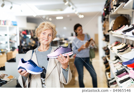 Portrait of a mature woman holding sports sneakers Portrait of a mature woman holding sports sneakers 84965546