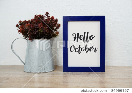 Hello October typography text with artificial plant decoration on wooden table and white wall background 84966597