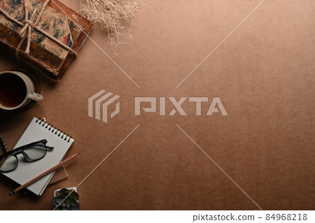 Top view notebook, glasses, coffee cup and vintage books on brown background. 84968218