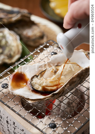 Sprinkle soy sauce on the grilled oysters Sprinkle soy sauce on the grilled oysters 84969504