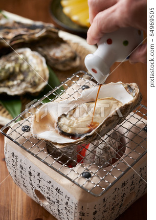 在烤牡蠣上撒上醬油 84969505