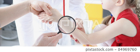 Doctor examining baby skin on hand with magnifying glass in clinic Doctor examining baby skin on hand with magnifying glass in clinic 84969760
