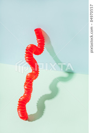 The curved pop tube stands leaning against the wall. Modern still life with antistress toy The curved pop tube stands leaning against the wall. Modern still life with antistress toy 84970557