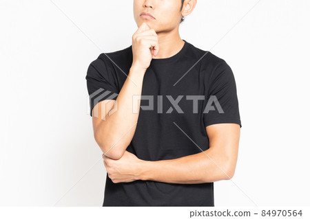 A man wearing a troubled black T-shirt standing in front of a white background 84970564