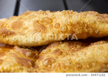 The chebureks pasties on a wooden table macro, the texture of fried dough in oil. 84971282