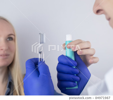The dentist advises the girl on how to brush her teeth properly. The doctor teaches and explains. Isolated on white background. In the hands of a toothbrush and paste. 84971987