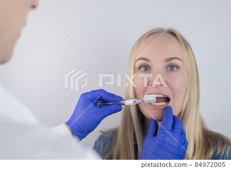 The dentist advises the girl on how to brush her teeth properly. The doctor teaches and explains. Isolated on white background. In the hands of a toothbrush and paste. The dentist advises the girl on how to brush her teeth properly. The doctor teaches and explains. Isolated on white background. In the hands of a toothbrush and paste. 84972005