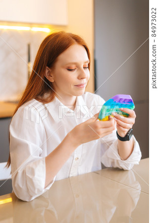 Vertical portrait of attractive redhead young woman playing fidget toy new trendy silicone toy anti stress pop it and simple dimple. Vertical portrait of attractive redhead young woman playing fidget toy new trendy silicone toy anti stress pop it and simple dimple. 84973022
