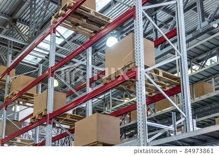 goods are on the shelves of a large warehouse of products 84973861