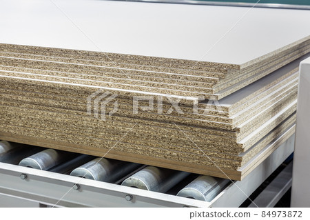 particle boards are stacked on a wood-cutting machine 84973872
