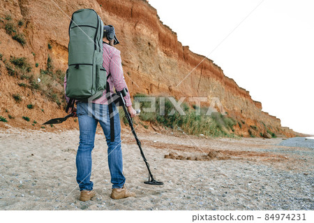 Man with metal detector searching for lost treasures on the beach 84974231
