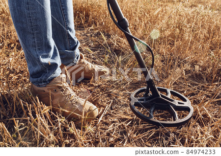 Man with metal detector equipment searching for metal goods in the field Man with metal detector equipment searching for metal goods in the field 84974233