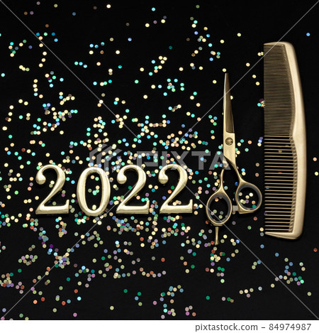 Figures 2022 scissors and comb with confetti on a dark background. Square greeting card of a hairdresser or hair salon. Figures 2022 scissors and comb with confetti on a dark background. Square greeting card of a hairdresser or hair salon. 84974987