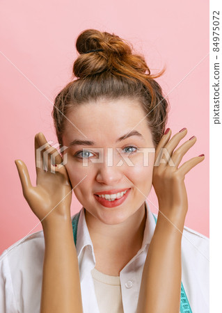 Close-up portrait of smiling girl, seamstress tailor holding mannequin's plastic hands isolated on pink background. Concept of job, hobby Close-up portrait of smiling girl, seamstress tailor holding mannequin's plastic hands isolated on pink background. Concept of job, hobby 84975072