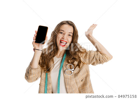 Close-up portrait of smiling young girl, dressmaker using phone isolated on white background. Concept of job, hobby 84975158