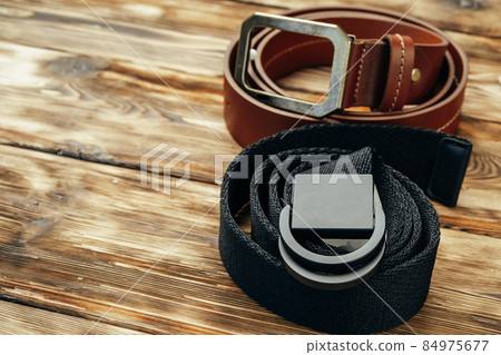 Fashionable male belt on brown wooden background Fashionable male belt on brown wooden background 84975677