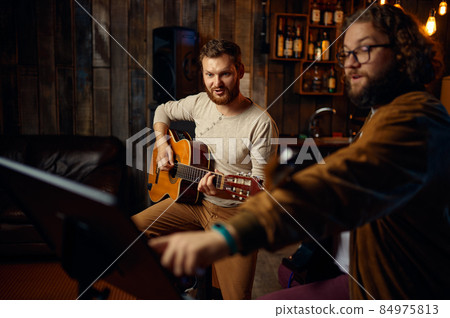 Teacher giving guitar lesson to young guy 84975813