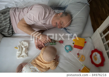 Cheerful senior grandfather playing with grandson at the bedroom Cheerful senior grandfather playing with grandson at the bedroom 84976218