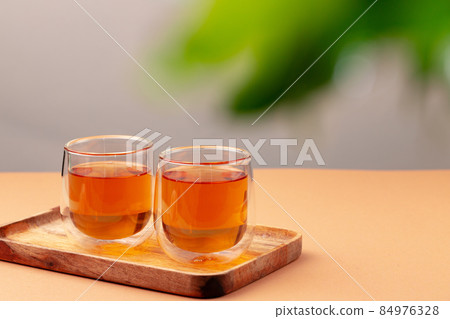 Two glass cups of black tea on beige table Two glass cups of black tea on beige table 84976328