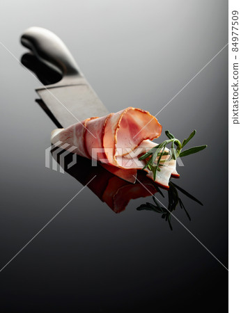 Bacon with rosemary on a kitchen knife. Bacon with rosemary on a kitchen knife. 84977509