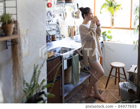 Cute lady drinking coffee in the kitchen Cute lady drinking coffee in the kitchen 84977693