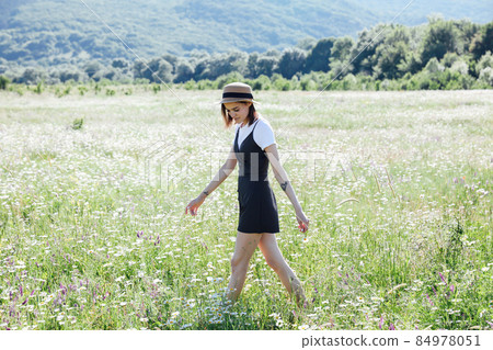 a beautiful woman walks in a field with chamomile flowers 84978051