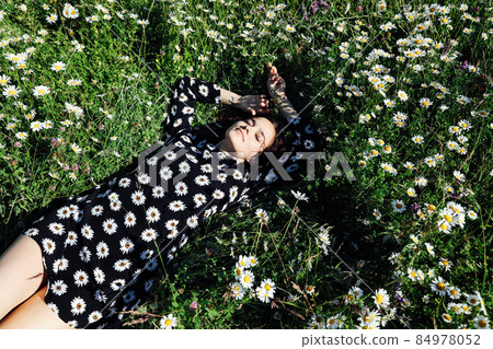 beautiful woman in lies in the grass with chamomile flowers 84978052