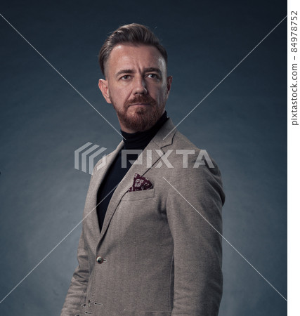 Portrait of a stylish elegant senior businessman with a beard and casual business clothes in photo studio isolated on dark background gesturing with hands Portrait of a stylish elegant senior businessman with a beard and casual business clothes in photo studio isolated on dark background gesturing with hands 84978752