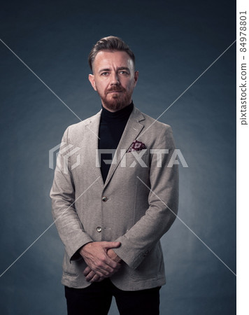 Portrait of a stylish elegant senior businessman with a beard and casual business clothes in photo studio isolated on dark background gesturing with hands Portrait of a stylish elegant senior businessman with a beard and casual business clothes in photo studio isolated on dark background gesturing with hands 84978801