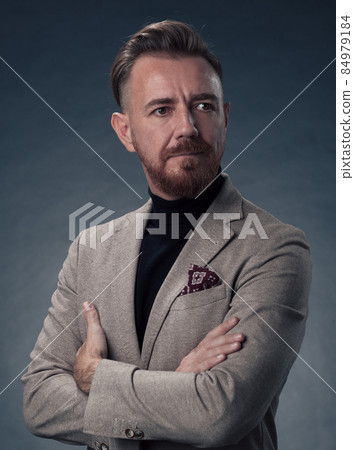 Portrait of a stylish elegant senior businessman with a beard and casual business clothes in photo studio isolated on dark background gesturing with hands Portrait of a stylish elegant senior businessman with a beard and casual business clothes in photo studio isolated on dark background gesturing with hands 84979184