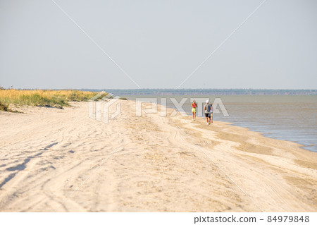 Selective focus from behind on a man running along the beach along the sea. Selective focus from behind on a man running along the beach along the sea. 84979848