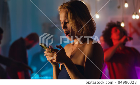 Woman sending voice message during party Woman sending voice message during party 84980328