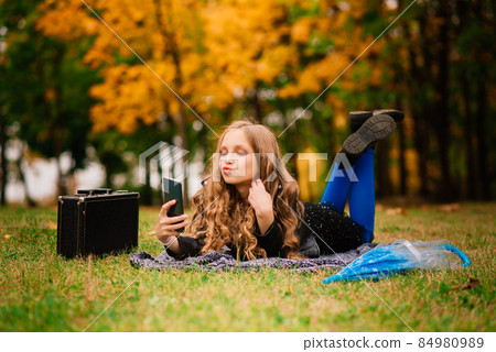 Cute stylish girl with long blonde hair in autumn park. Autumn kids fashion, lifestyle portrait. 84980989
