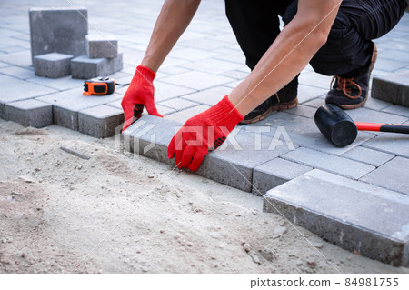 The master in yellow gloves lays paving stones The master in yellow gloves lays paving stones 84981755