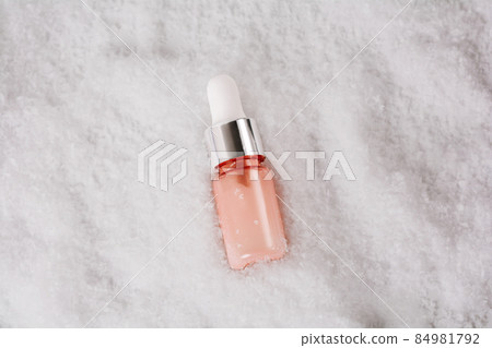 Cosmetics bottle with beauty product in the snow. Liquid skin or hair care product. Christmas and holiday concept. Top view and copy space 84981792