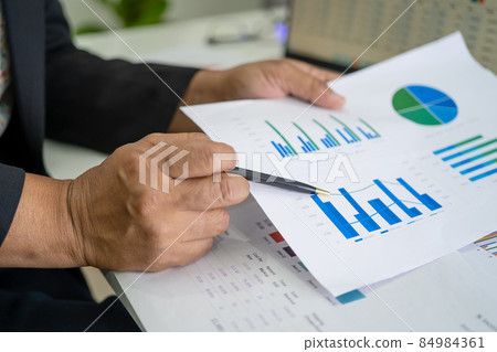 Asian accountant working and analyzing financial reports project accounting with chart graph and calculator in modern office, finance and business concept. 84984361