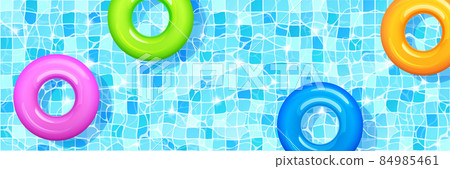 Swimming pool with colorful inflatable rings. 84985461