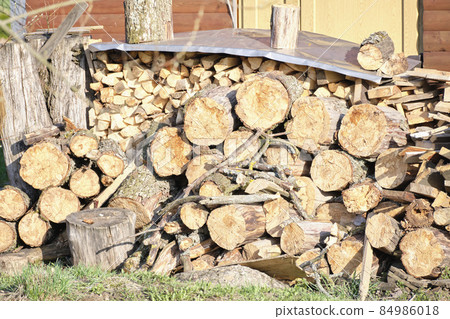 Pile of firewood into the distance the walls of the house 84986018