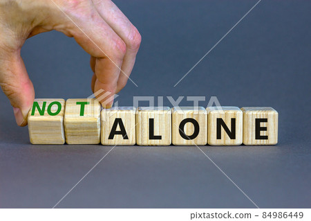 You are not alone symbol. Businessman turns wooden cubes and changes words alone to not alone. Beautiful grey table grey background, copy space. Business, support you are not alone concept. You are not alone symbol. Businessman turns wooden cubes and changes words alone to not alone. Beautiful grey table grey background, copy space. Business, support you are not alone concept. 84986449