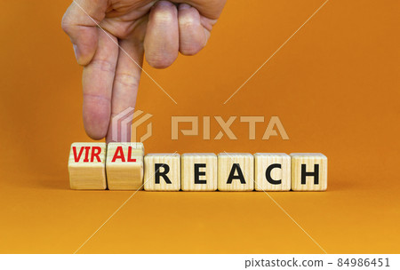 Viral reach symbol. Businessman turns wooden cubes and changes words 'reach' to 'viral reach'. Beautiful orange table, orange background, copy space. Business, viral reach concept. 84986451