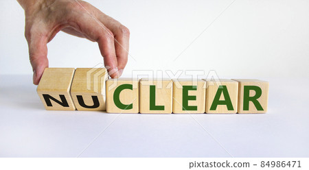 Nuclear or clear symbol. Businessman turns a cube and changes the word 'nuclear' to 'clear'. Beautiful white background. Nuclear or clear and business concept. Copy space. 84986471