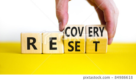 Recovery and reset symbol. Businessman turns cubes and changes the word 'recovery' to 'reset'. Beautiful yellow table, white background. Business and recovery - reset concept. Copy space. Recovery and reset symbol. Businessman turns cubes and changes the word 'recovery' to 'reset'. Beautiful yellow table, white background. Business and recovery - reset concept. Copy space. 84986618