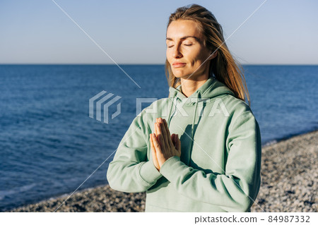 Close-up portrait of a woman meditating by the sea. Close-up portrait of a woman meditating by the sea. 84987332