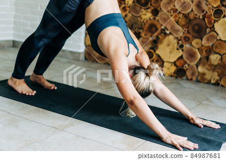 Young flexible wellness woman in sportswear working out on the mat at home 84987681