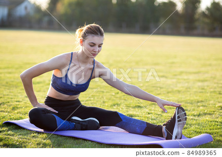 Young sportive woman exercising in morning field outdoors. Young sportive woman exercising in morning field outdoors. 84989365