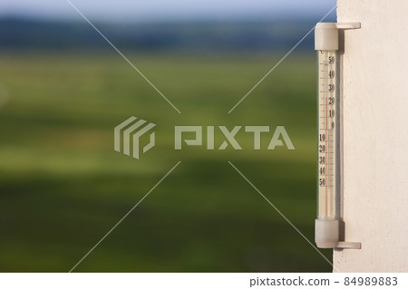 Thermometer celsius showing warm temperature on blurred green ba Thermometer celsius showing warm temperature on blurred green ba 84989883